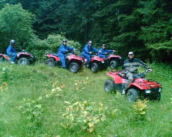 Grup de participanți în pelerine albastre pe ATV-uri roșii, la marginea pădurii