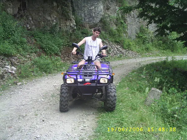 Tânăr conducând un ATV mov pe un drum forestier pietruit