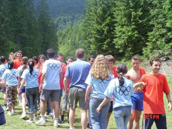 Echipe în tricouri albastre și portocalii adunate în poiană pentru un concurs