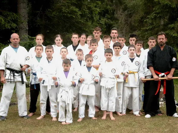 Grupă de karate în kimonouri albe pozând alături de instructori