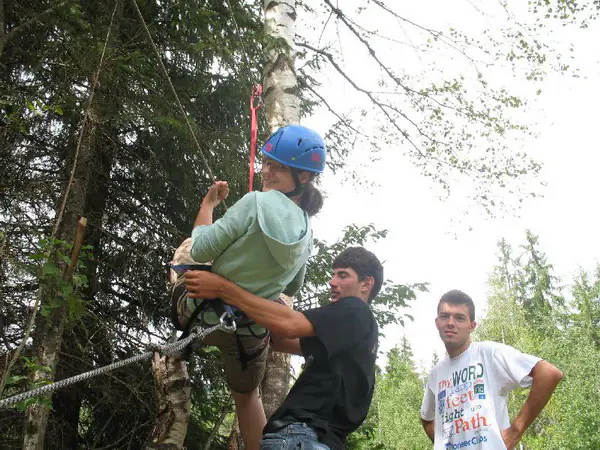 Instructor prinzând hamul unui tabărăș de cablul tirolienei