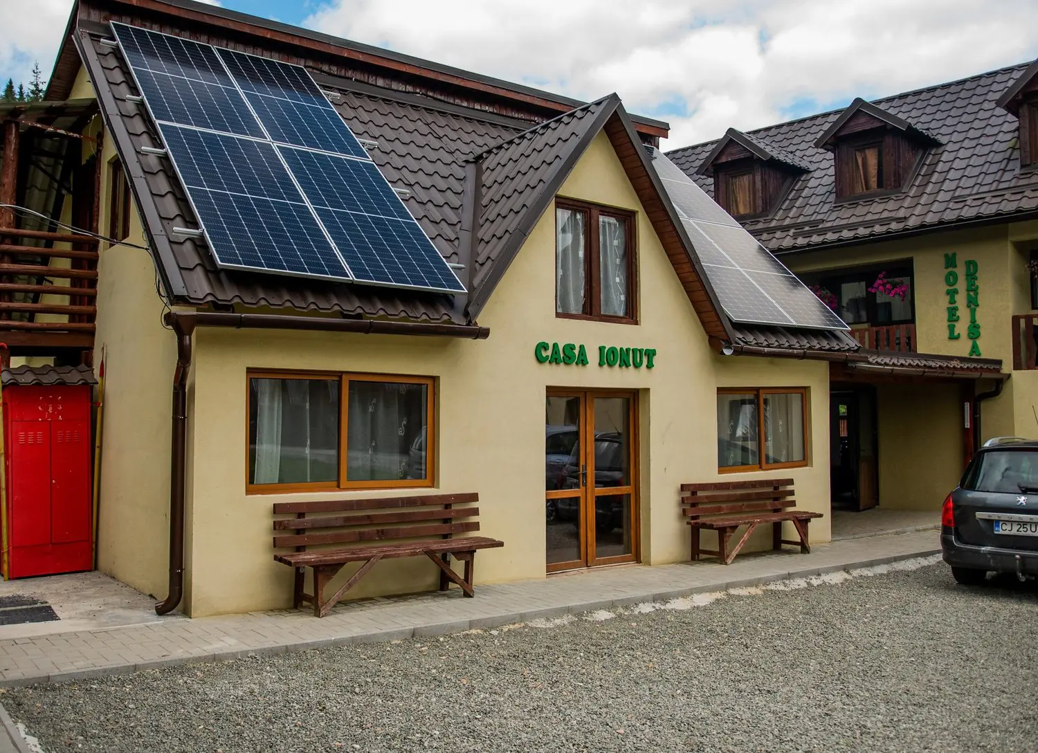 Casa Ionuț, cu panouri solare pe acoperiș și bănci de lemn la intrare