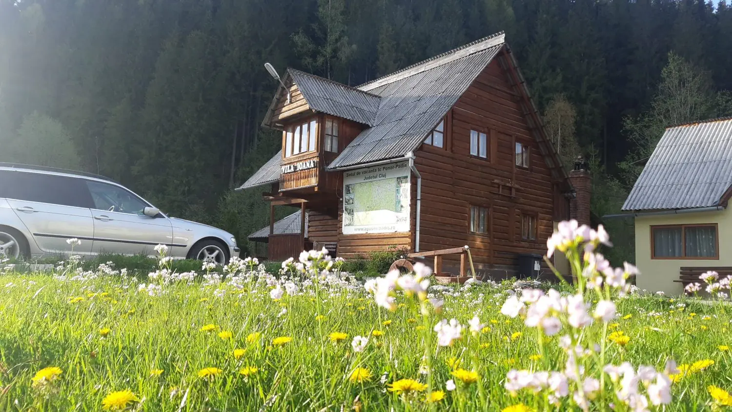 Vila Ioana, cabană din lemn cu flori de primăvară în față
